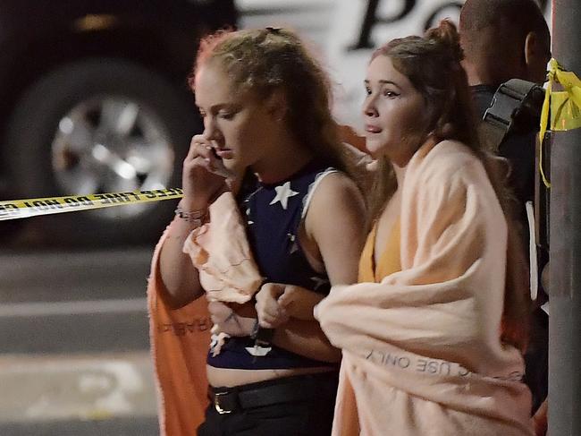 People walk away from the scene Thursday, Nov. 8, 2018, in Thousand Oaks, Calif. where a gunman opened fire Wednesday inside a country dance bar crowded with hundreds of people on 