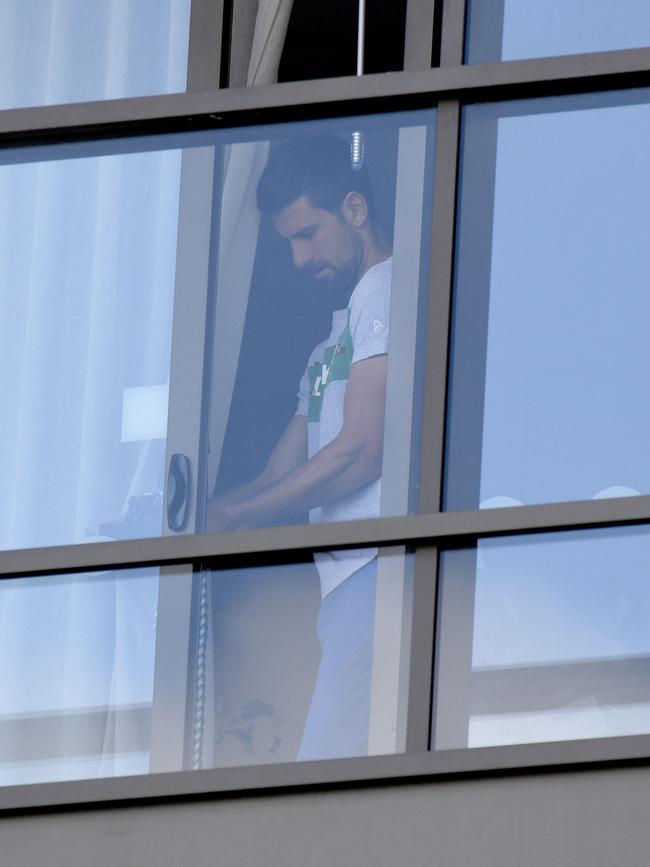 Novak Djokovic ties back the curtain in the window of his quarantine hotel. Picture: NCA NewsWire/Naomi Jellicoe