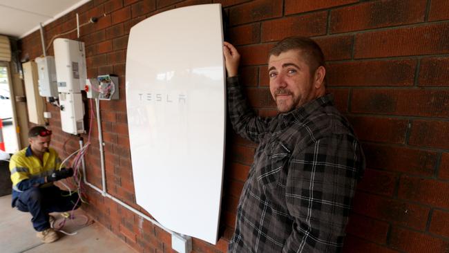 Apprentice electrician Adam Maxwell-Davis installs a Tesla home battery at Steve Hendy’s home at Salisbury Plains. Picture: Kelly Barnes
