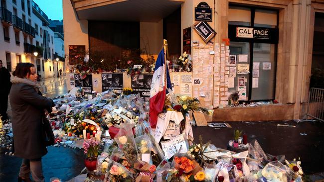 <br/>A woman looks at floral tributes left outside the Charlie Hebdo magazine offices in Paris for victims of the 2015 massacre at the weekly satirical paper which left 12 dead. Picture: AFP