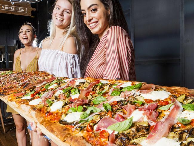 Mikaela Cherise (23), Emmalee Stevenson (19) and Kara Maree Cassar (22) with a 3 Metre Pizza at Criniti's Westfield Chermside. Photo Lachie Millard