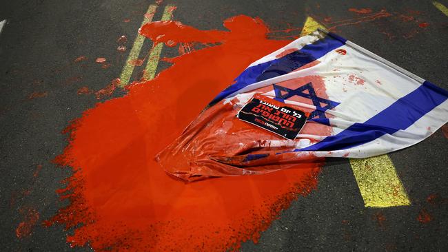 An Israeli flag is covered in red paint as relatives and supporters of hostages are angry at the Israeli government following the killings. Picture: AFP