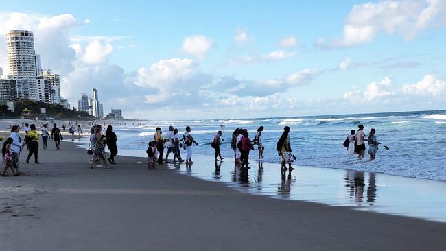 People throw flowers into the water at the memorial for Ravneet Kaur at Surfers Paradise this evening.