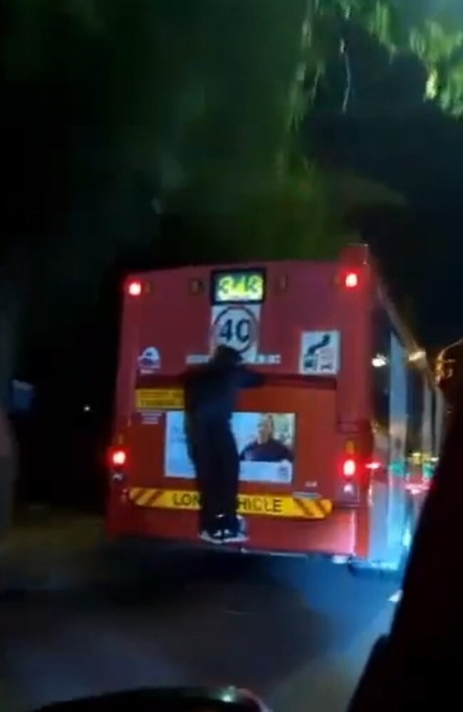 A daring ‘bus surfer’ was captured on film taunting motorists in Sydney.