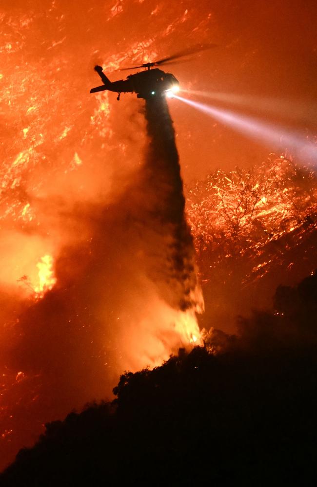 A fire fighting helicopter drops water on the Palisades fire near the Mandeville Canyon neighbourhood on January 11. Picture: Patrick T. Fallon/AFP