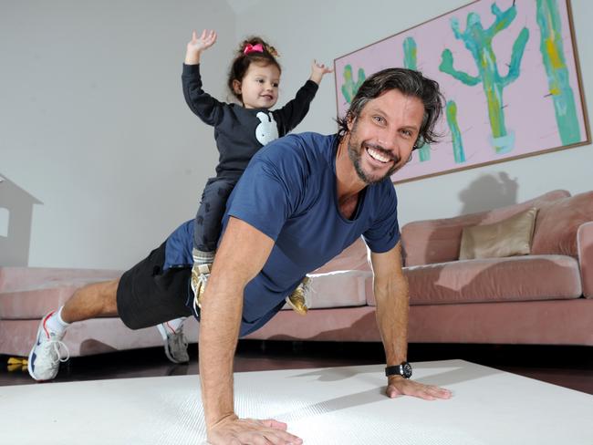 Sam Wood exercises with his 2 1/2 year-old daughter Willow at their Brighton home. Picture: Andrew Henshaw