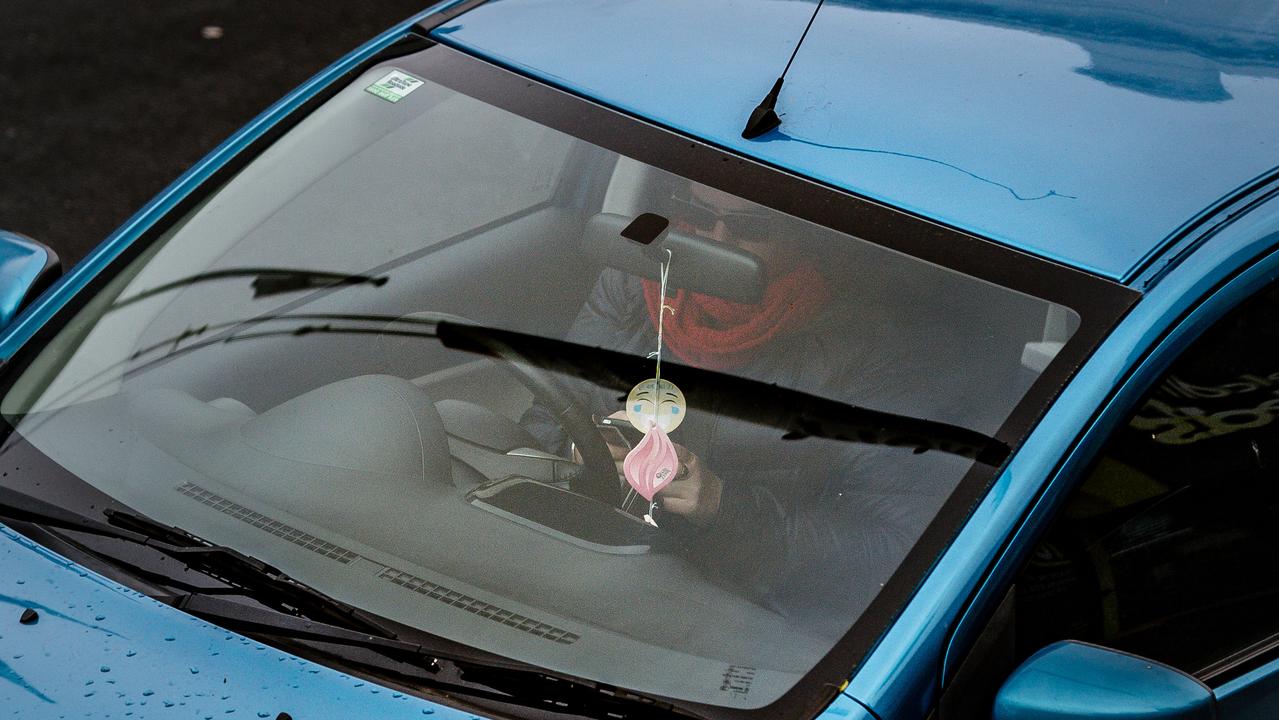 A woman checks her phone while driving through the CBD. Picture: AAP Image / Morgan Sette