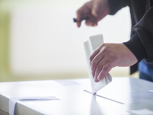 Hand of a person casting a ballot at a polling station during voting. election voting vote polling poll generic Townsville