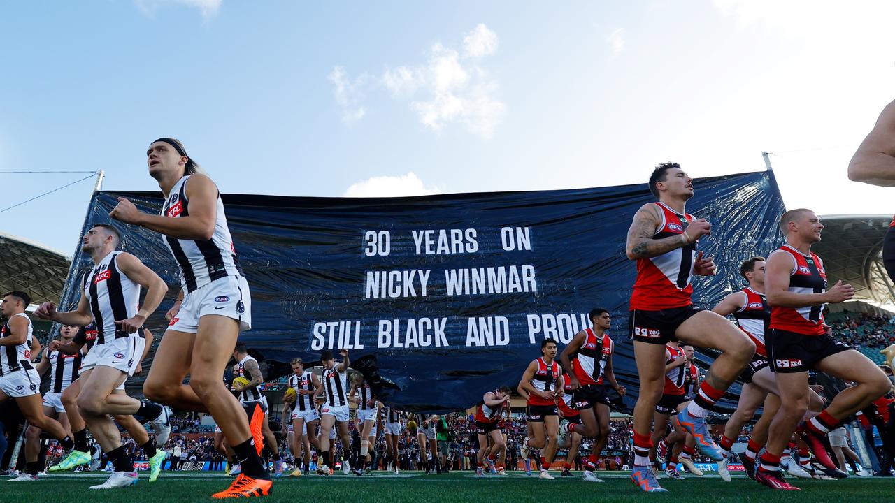 Players from both teams enter through a joint banner ahead of Collingwood v St Kilda