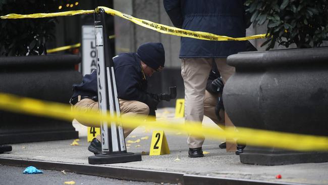 Police place bullet casing markers outside of a Hilton Hotel in Midtown Manhattan where United Healthcare CEO Brian Thompson was fatally shot.