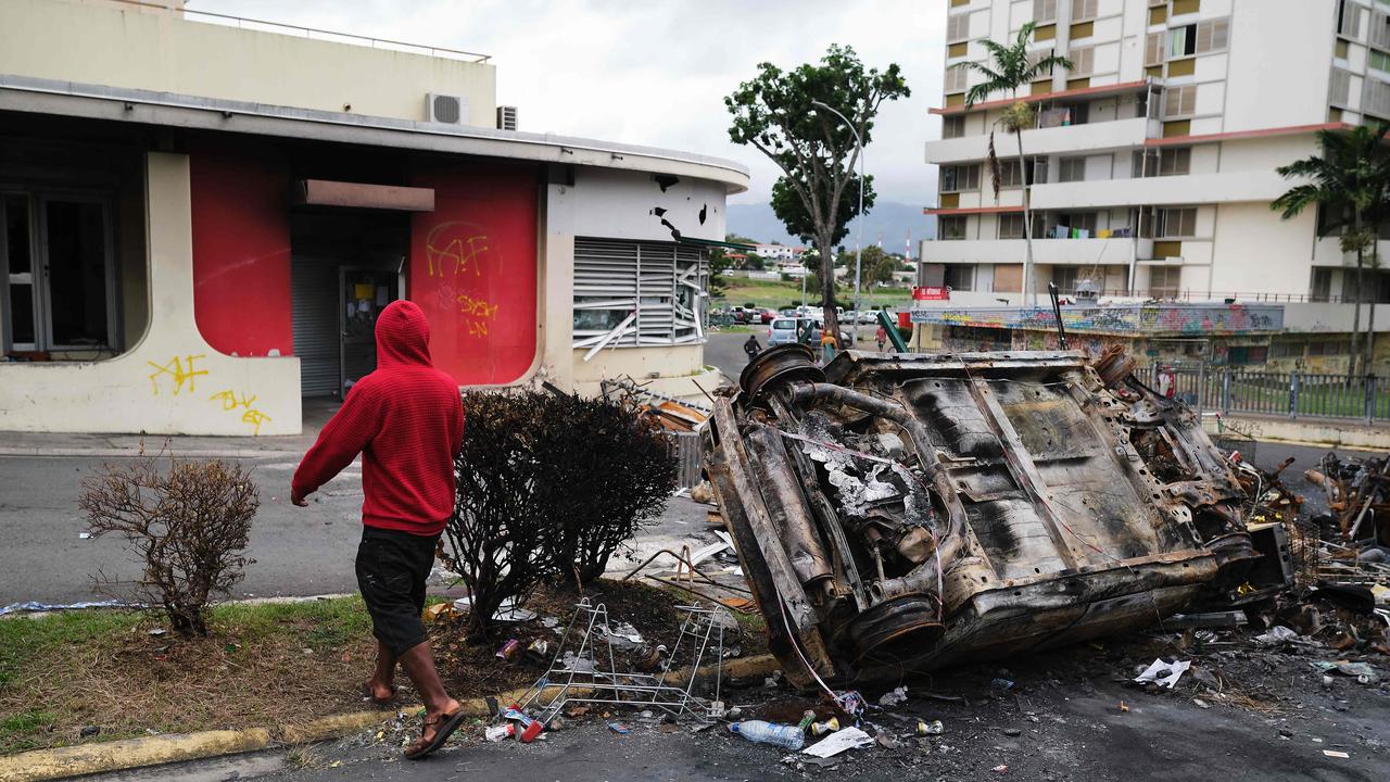 A man walks past a burnt vehicle at an independantist roadblock at Magenta Tour district in Noumea, France's Pacific territory of New Caledonia, on May 22, 2024. Picture: Theo Rouby/AFP