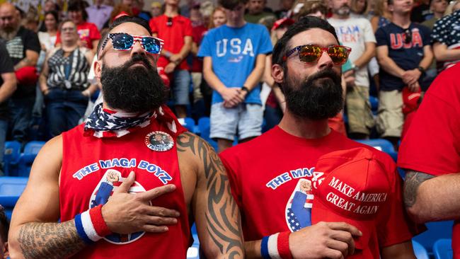 Nick Passano (L), a tattooed Millennial cryptocurrency investor, holds his hand to his heart during a Trump rally. Picture: AFP).