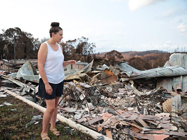 Katie Anderson-Brown in front of her burnt down home in Conjola Park overlooking Conjola Lake. Picture: Adam Yip