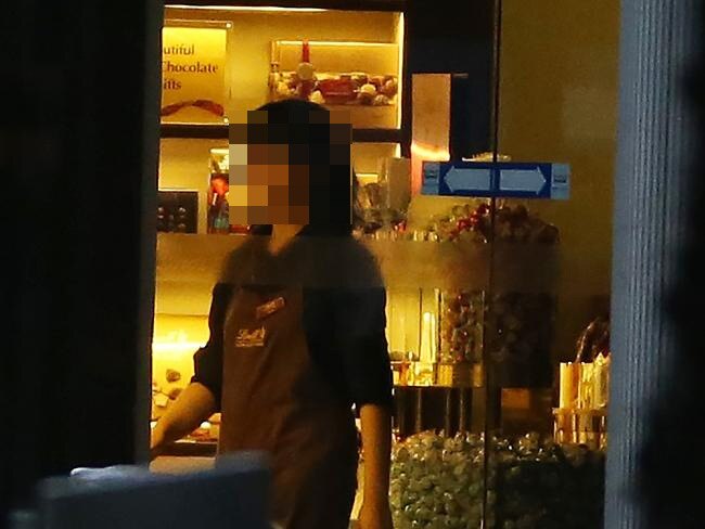 A staff member goes to the front door to turn off the lights in the Lindt cafe where hostages are being held at gunpoint in Martin Place. Picture: Craig Greenhill