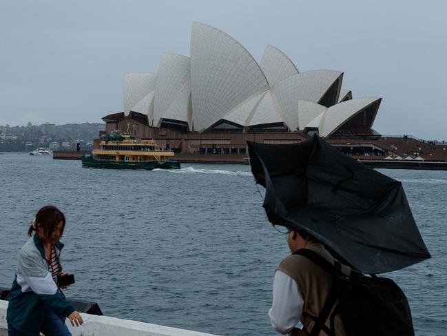 SYDNEY, AUSTRALIA - NewsWire Photos MAY 11 2024. People brave the weather to sightsee around the opera house & harbour bridge. Wild weather will continue to batter NSW, with unrelenting rain that has lingered over Sydney forecast to stick around, and severe thunderstorms predicted over the weekend. Picture: NCA NewsWire / Max Mason-Hubers