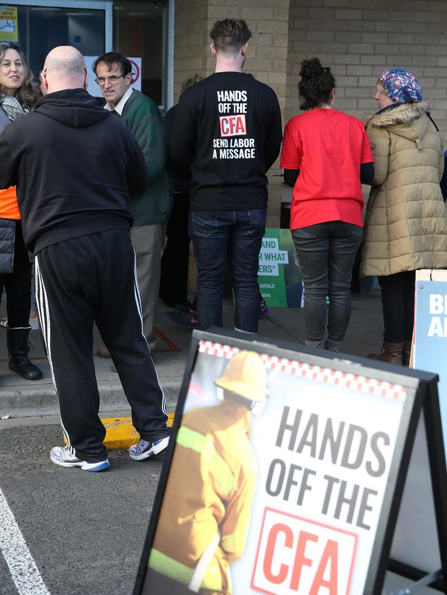 A volunteer hands out how to vote info wearing a black CFA shirt at a pre-poll voting centre. Picture: Peter Ristevski