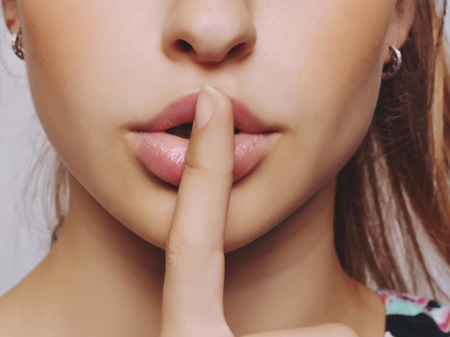 Closeup portrait of beautiful young woman with finger on lips.