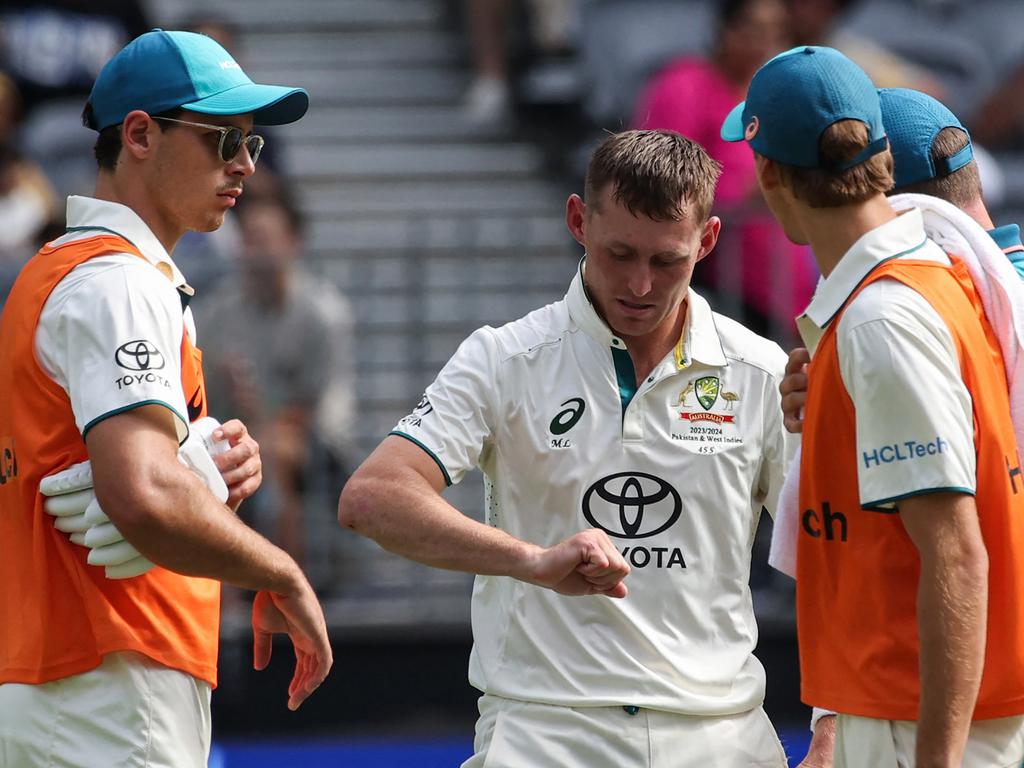 Australia's Marnus Labuschagne (C) inspects his injured finger.