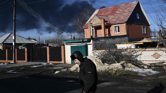 A man walks in a street as black smoke rises from a military airport in Chuguyev near Kharkiv. Picture: Aris Messinis / AFP