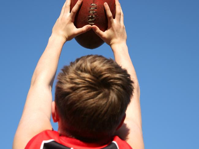 Young boy takes a mark catch above his head during an Australian Rules football AFL match. Generic image Picture: iStock