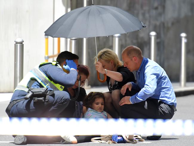 A young girl is treated at the scene, while an umbrella is held over her to protect from the sun. Picture: Tony Gough