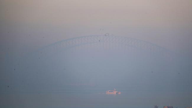 The Sydney Harbour Bridge is almost invisible behind the smoke. Picture: John Grainger