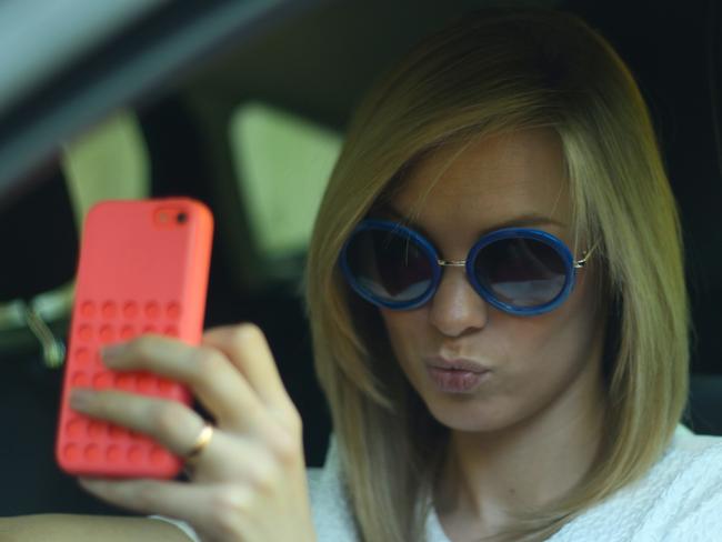 Woman taking a "selfie" while driving. Photo: Supplied (Ford UK, 2014).‏‎ Posed by model