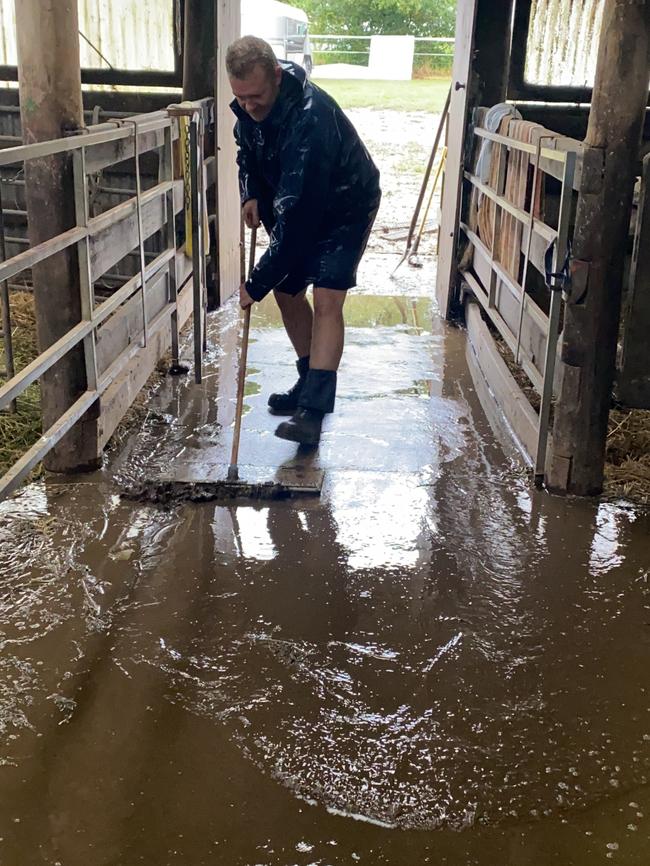 Rubey’s dad sweeping up the rain that flooded a barn at their property.