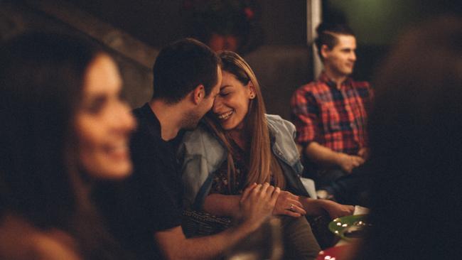 Photo of a lovely couple during the dinner party with friends, in an outdoors bistro