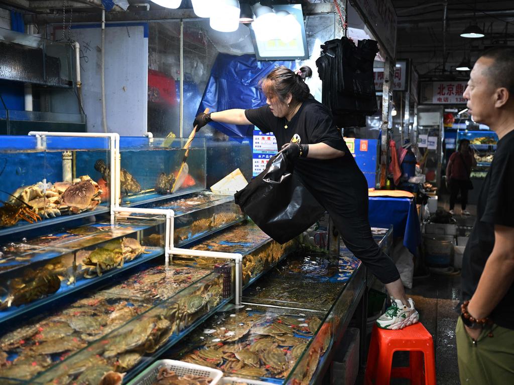 A vendor collects a fish for a customer at a wholesale fish market in Beijing as fish imports from Japan are banned by the Chinese government. (Photo by GREG BAKER / AFP)