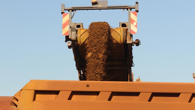 An earth mover receives iron ore from a surface miner in the mine pit at Fortescue Metals Group Ltd.'s Cloudbreak operation in the Pilbara region of Western Australia, on Monday, July 25, 2011. Fortescue Metals Group, Australia's third-biggest producer of iron ore, will release their full-year earnings on August 19. Photographer: Carla Gottgens/Bloomberg