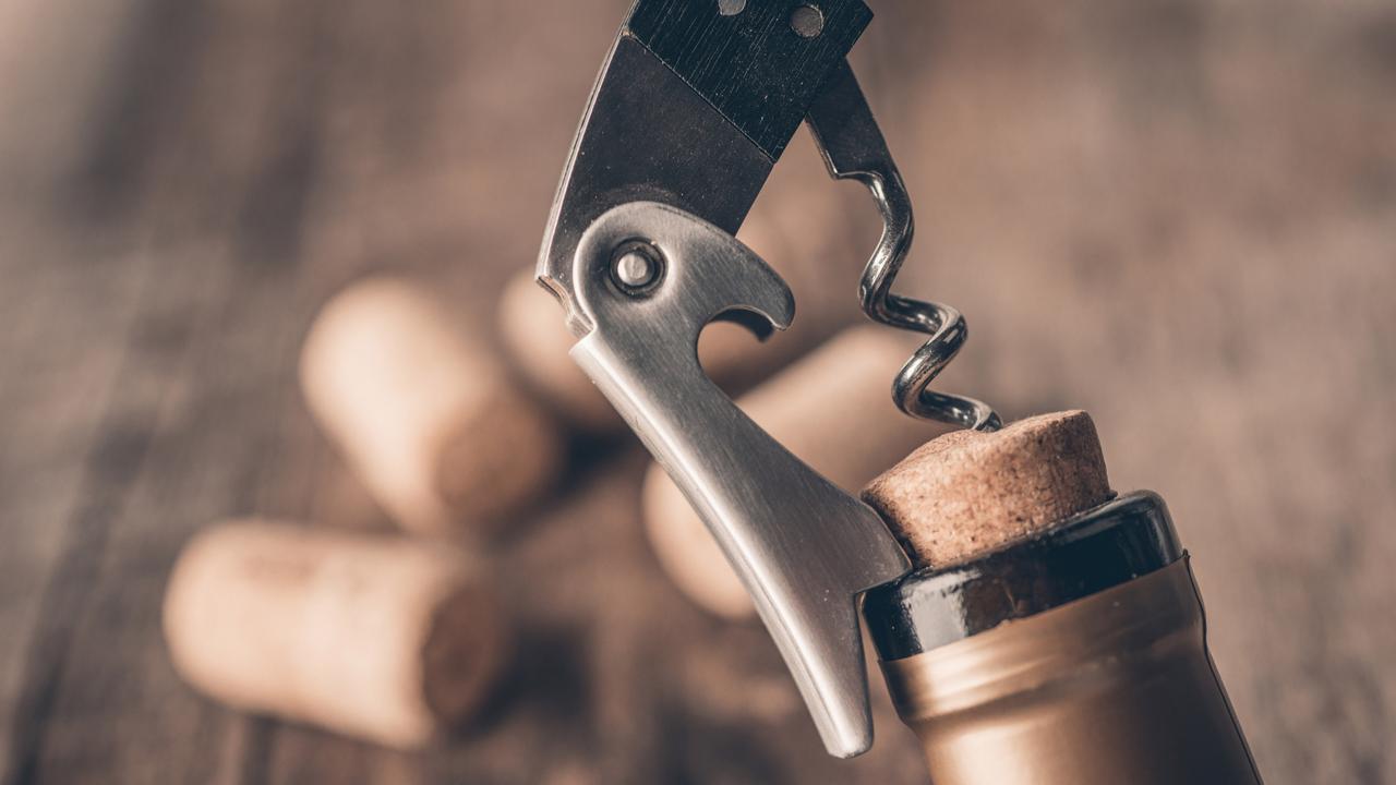 Corkscrew and bottle of wine on the board