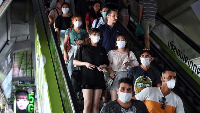 File: People wearing face masks ride the escalators at a BTS Skytrain station in Bangkok (Photo by Lillian SUWANRUMPHA / AFP)