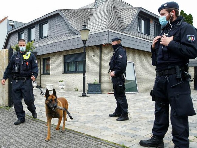 A German police officer and his sniffing dog leave the yard of a villa following a police raid as part of Operation Trojan Shield in Leverkusen, Germany. Picture: Reuters