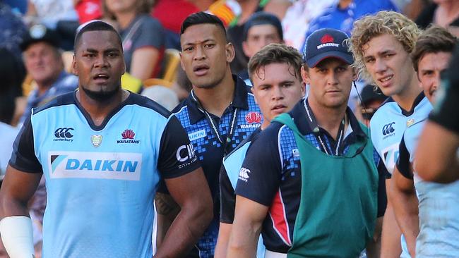 Waratahs star Israel Folau (second left) looks on from the bench.