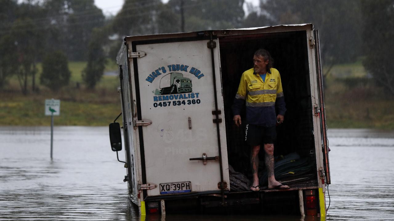 A man gets help from his neighbour to rescue his truck on Elizabeth MacArthur Ave in Camden South. An evacuation order is in place for parts of Camden as over 150mm of rain has fallen in the last 24 hours and the Nepean River bursts it banks. Picture: Jonathan Ng