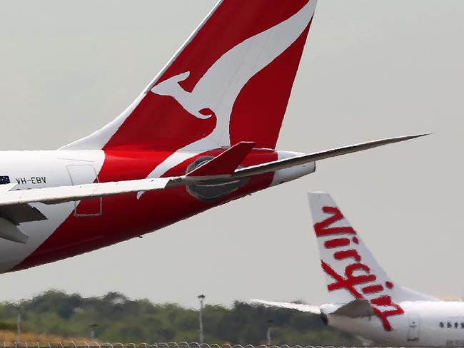 A Qantas Airways Ltd. aircraft, left, and a Virgin Australia Holdings Ltd. aircraft taxi on the runway at Sydney Airport in Sydney, Australia, on Wednesday, Feb. 26, 2014. Qantas, Australia's biggest airline, and second-ranked Virgin Australia are scheduled to report half-year earnings on Feb. 27 and Feb. 28 respectively. Photographer: Brendon Thorne/Bloomberg