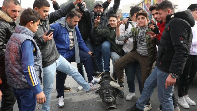 Syrians pose with a vandalized statue of Hafez al-Assad, father of Bashar al-Assad, in Umayyad Square in Damascus.