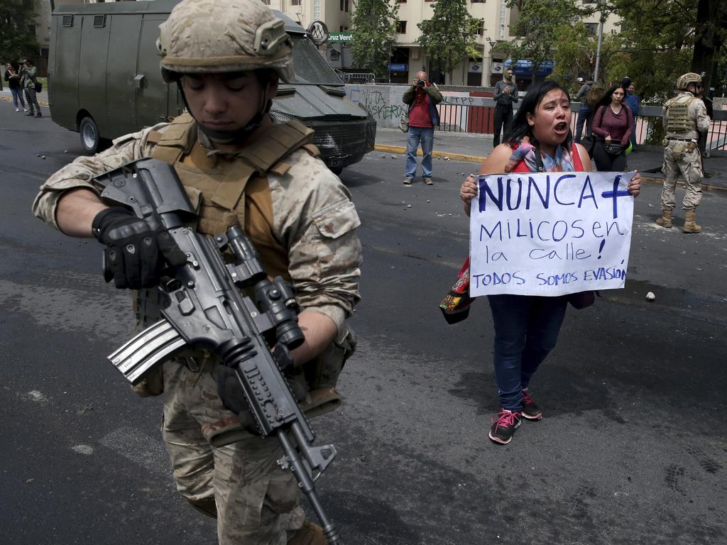 A woman holds a sign next to a soldier that reads in Spanish "Never again army in the streets" after a night of riots that forced a state of emergency. Picture: AP Photo