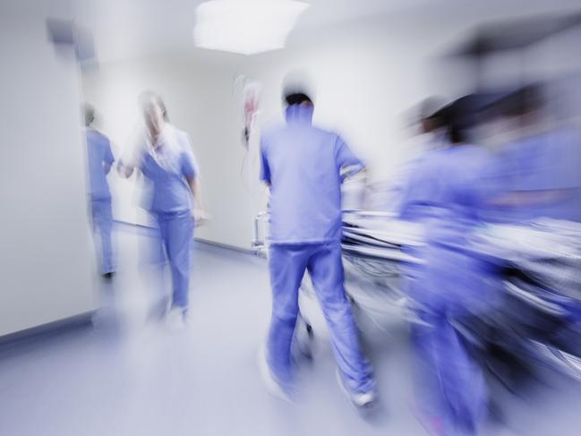 Doctors and nurses pulling hospital trolley,