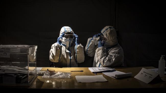 Election workers clean their fogged goggles while waiting for voters at a polling station during regional Catalan elections over the weekend. Picture: Getty Images