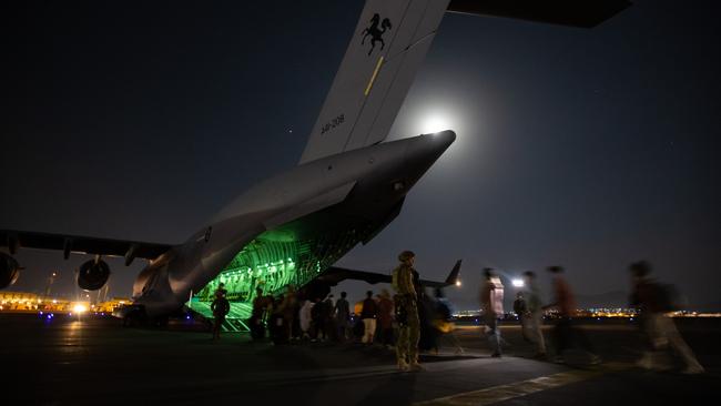 Australian citizens and visa holders form a line to board the Royal Australian Air Force C-17A Globemaster as Australian Army Infantry personnel provide security at Hamid Karzai International Airport. Picture: ADF