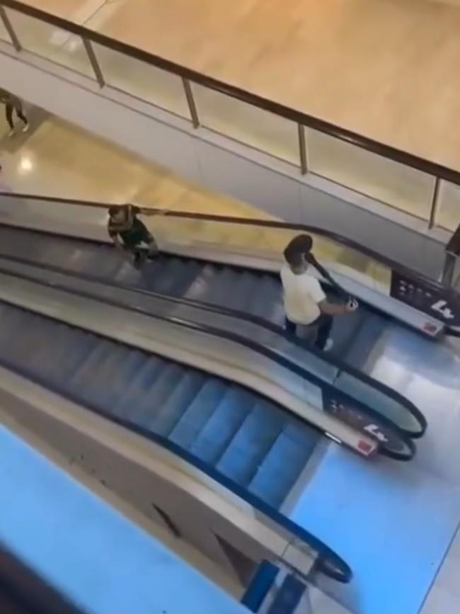 A member of the public, armed with a bollard, attempts to stop the attacker, right, on an escalator in the centre.