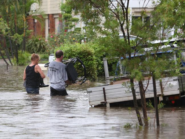 Oxley residents make their way into their flooded home. Picture: Marc Robertson