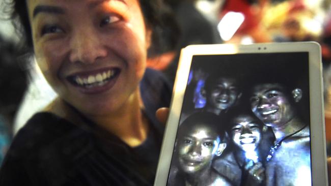 Noy holds up a picture of her son Dom, centre, shining a light, alongside his teammates during their cave ordeal.