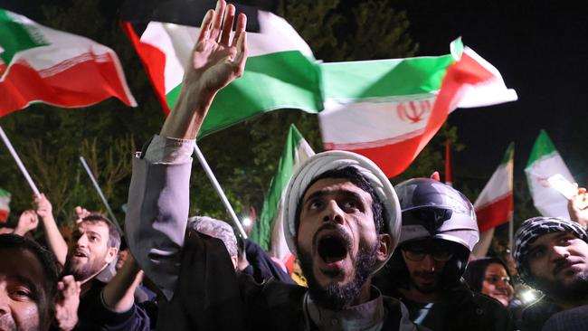 Demonstrators wave Iran's flag and Palestinian flags as they gather in front of the British Embassy in Tehran on April 14.