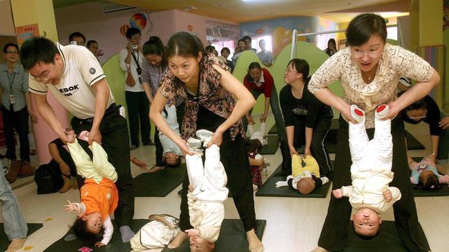 Chinese parents perform stretching exercises with their babies at a centre in southeast China. Beijing’s reluctance to publicise figures showing Chinese women having fewer children stretches back several years. Picture: AFP