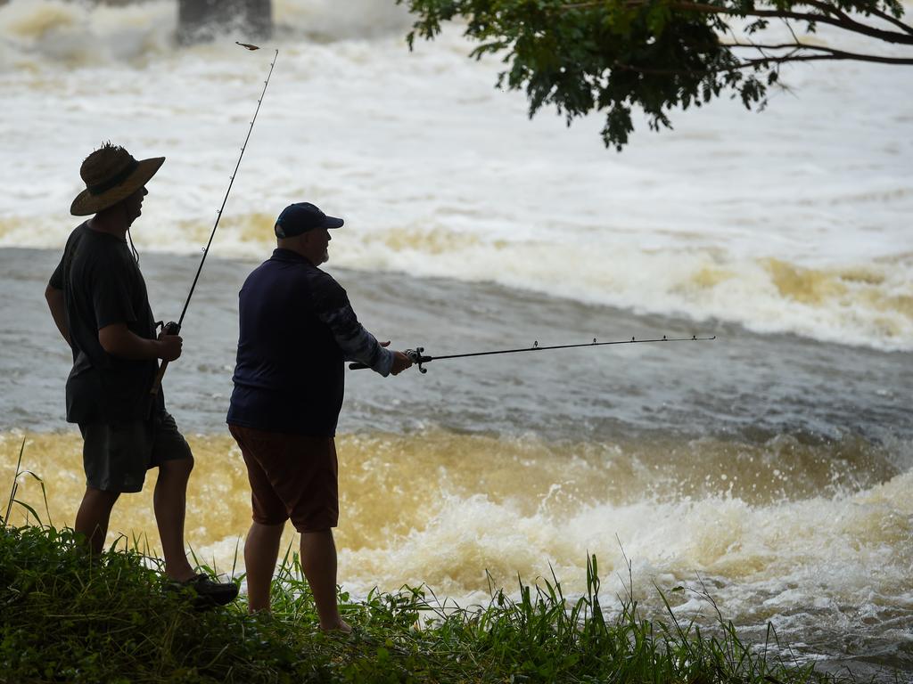 Locals fish around the raging Aplins Weir in Annandale as water flows from Ross dam. Picture: Scott Radford-Chisholm/NCA NewsWire