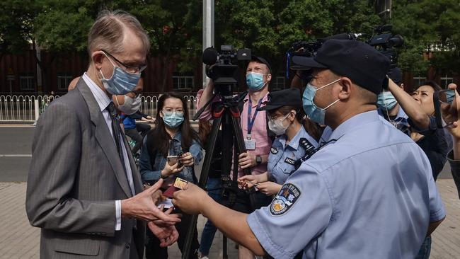 A Chinese police officer returns an ID card to Australian Ambassador to China Graham Fletcher, left, as he arrives at the Beijing Second Intermediate People's Court before the trial of Australian academic Yang Jun, also known as Yang Hengjun, on espionage charges today. Picture: AFP