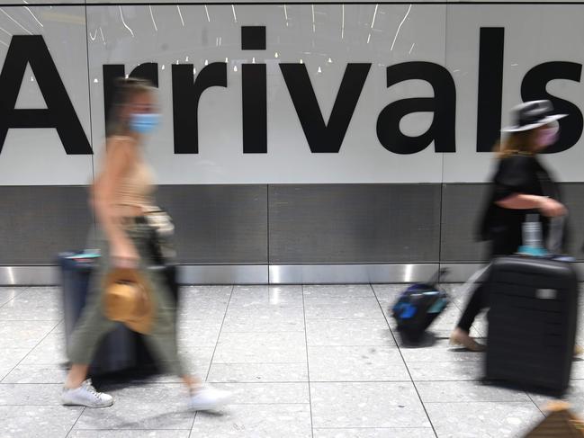 Passengers wearing face masks as a precautionary measure against COVID-19, walk through the arrivals hall after landing at London Heathrow Airport in west London, on January 15, 2021. - International travellers will need to present proof of a negative coronavirus test result in order to be allowed into England, or face a Â£500 ($685, 564 euros) fine on arrival, from January 18. (Photo by DANIEL LEAL-OLIVAS / AFP)